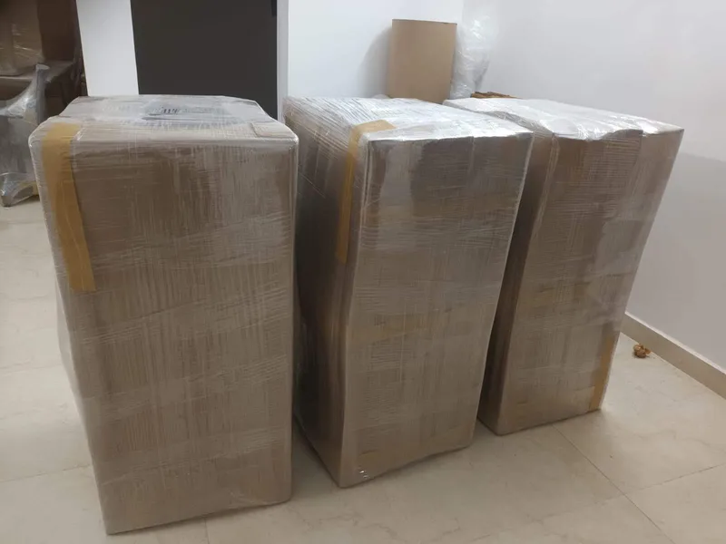 Three household storage cabinets wrapped in corrugated board lined up in hallway