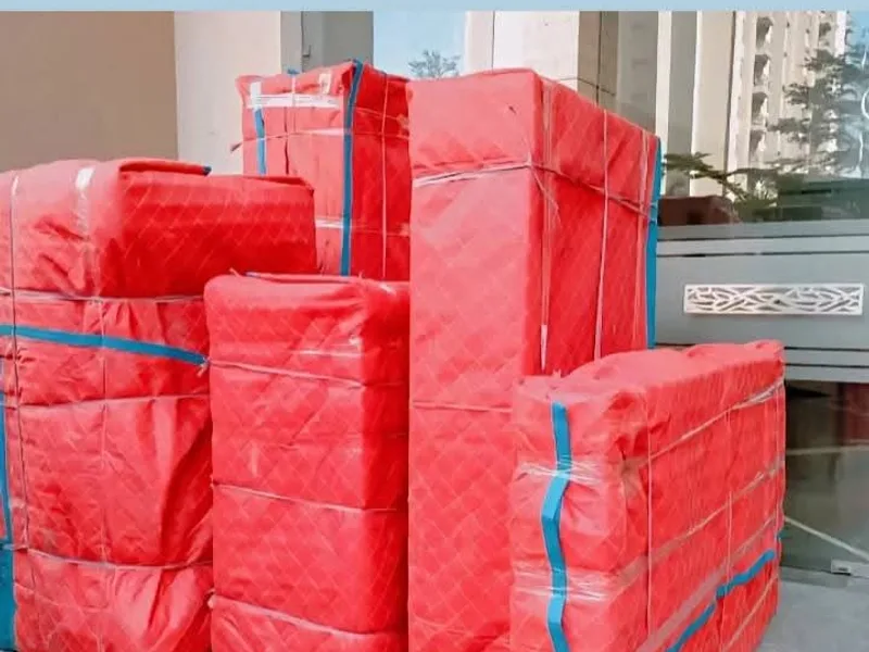 Household goods bundled with protective red stretch film and blue tie-down straps