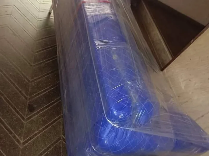 Sectional sofa unit completely sealed in blue stretch wrap in building corridor