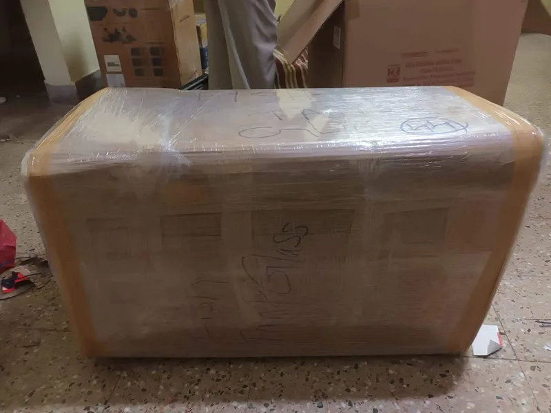 Bulky furniture module wrapped in brown paper and heavy-duty clear stretch film