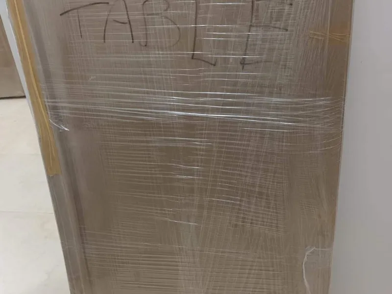 Flat glass tabletop panel wrapped in protective cardboard and stretch film