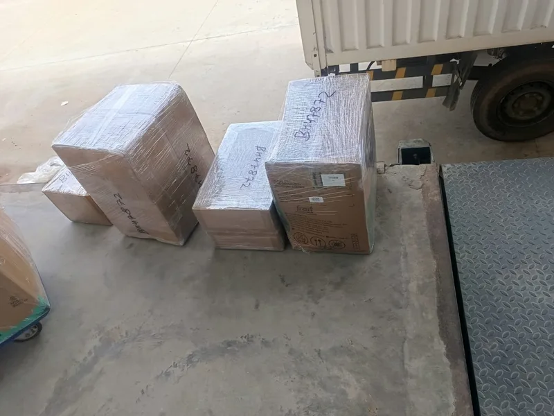 Packed shipping cartons labeled with consignment codes at vehicle loading dock