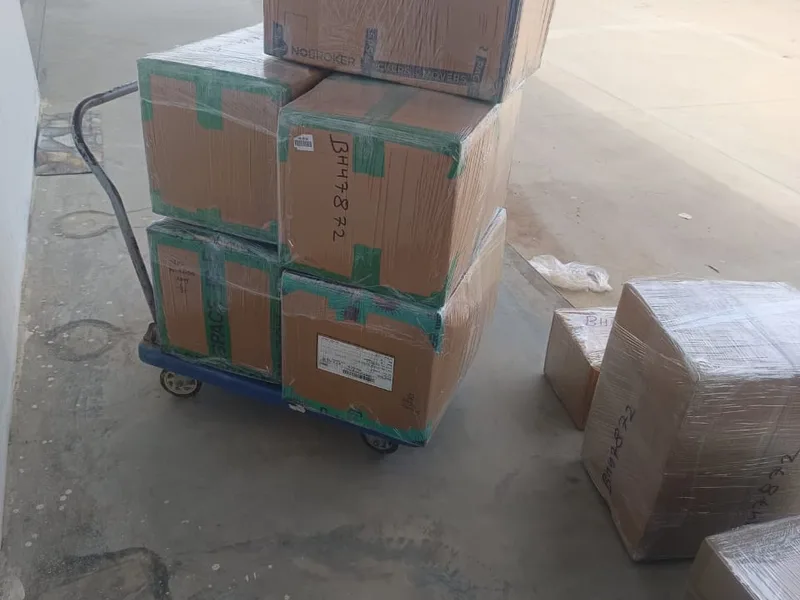 Moving worker moving stacked cardboard cartons on a heavy-duty hand trolley