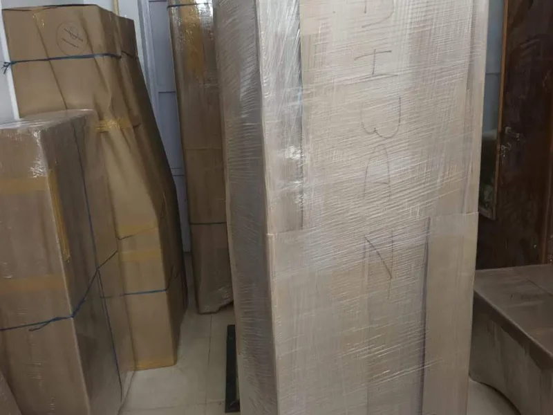 Tall wooden wardrobe wrapped in protective film stored in warehouse facility